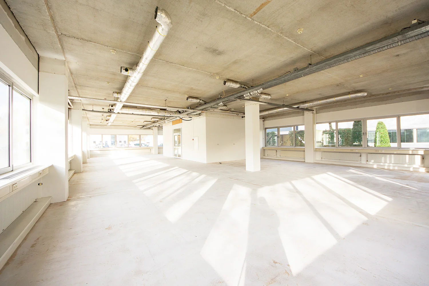 Lichte, lege kantoorruimte aan de Huis-ter-Heideweg met zichtbare plafonds en grote ramen.